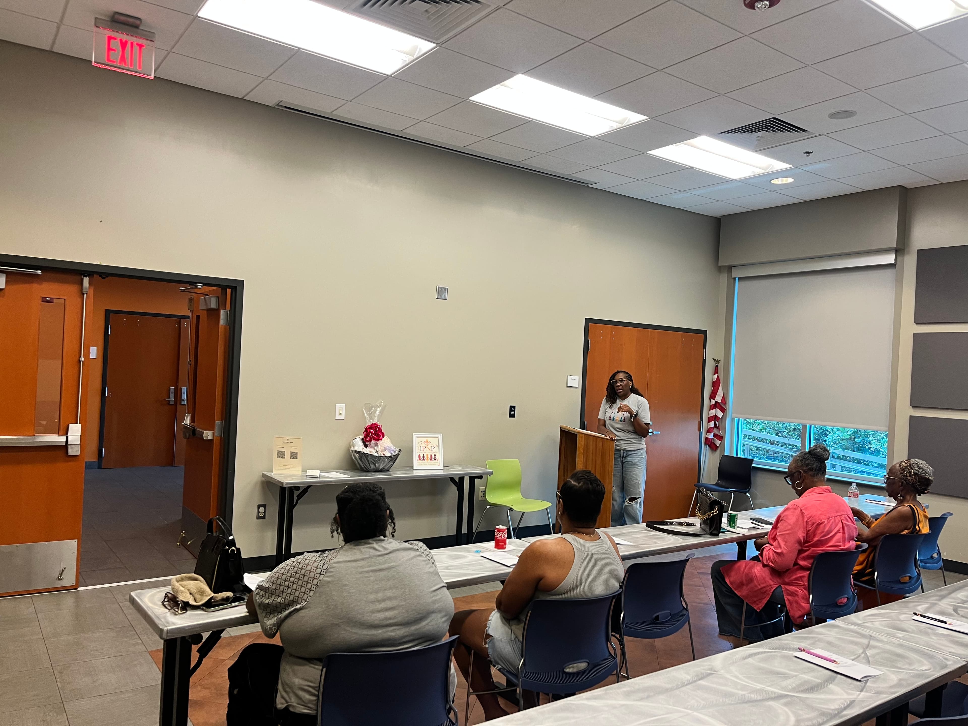 Tiffany presenting at the Houma meeting with the IPNP sign and gift basket visible