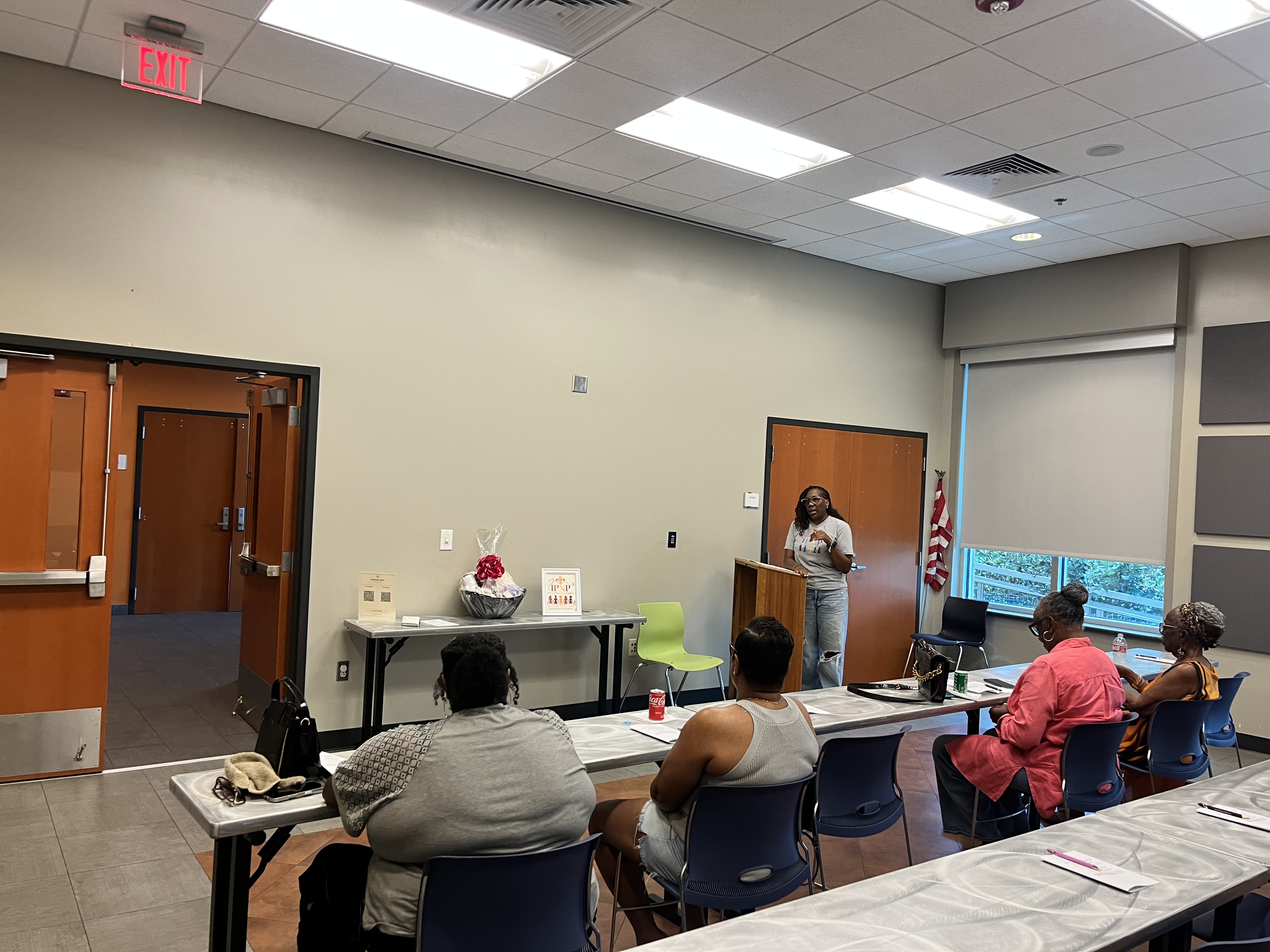 Tiffany presenting at the Houma meeting with the IPNP sign and gift basket visible