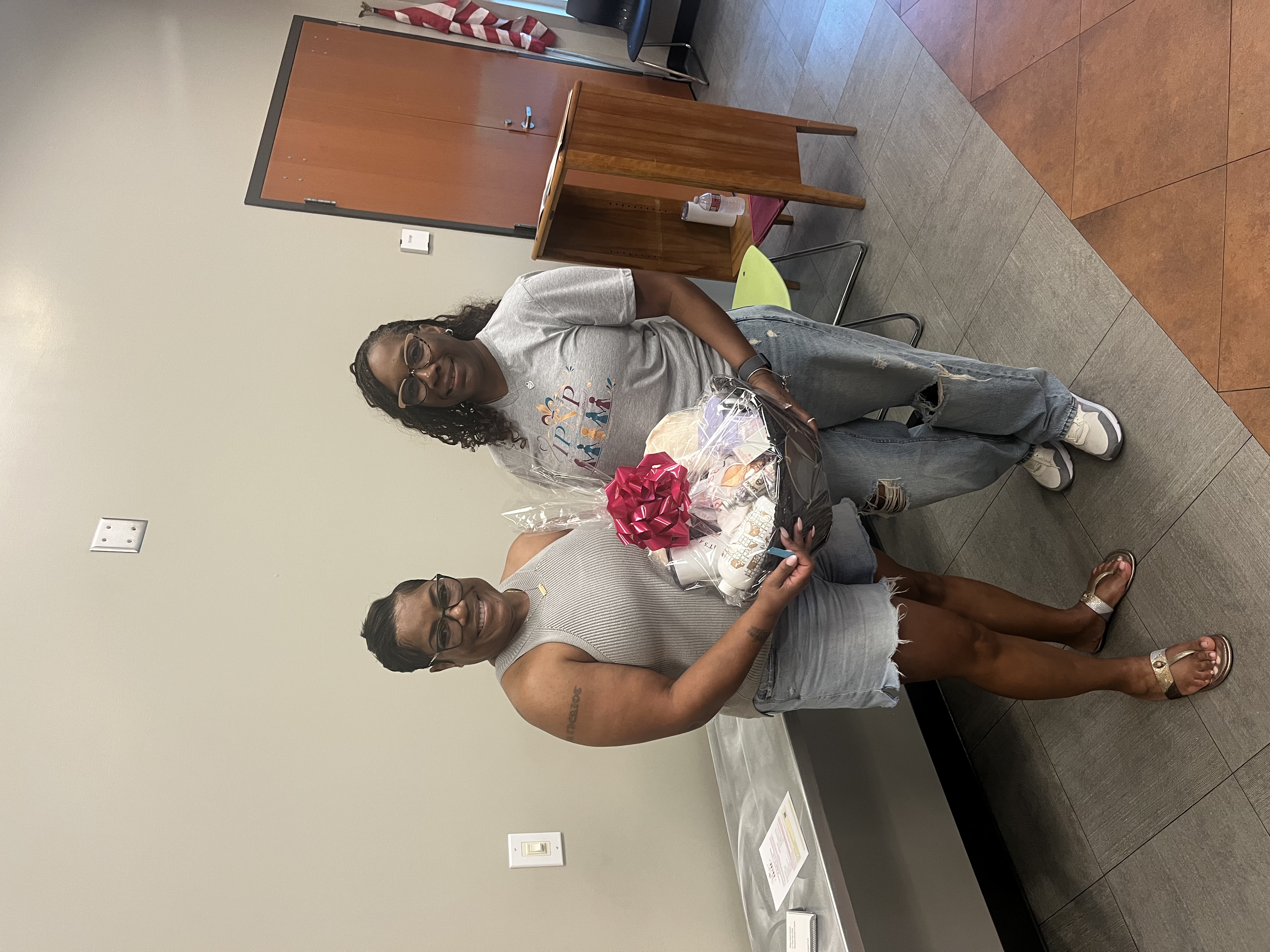 Two women holding the Houma meeting prize gift basket